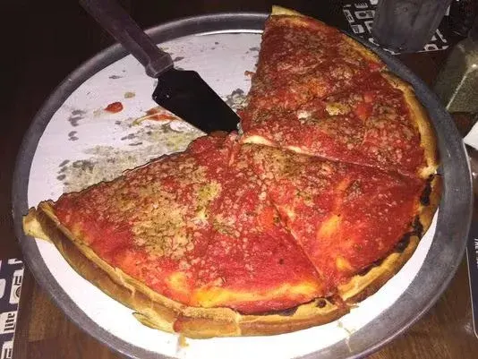 Large pepperoni pizza on a round tray with a pizza cutter.