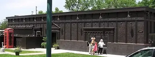 Historical black wall with people standing next to it and a red telephone booth nearby.